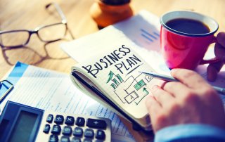 Business owner reviewing a detailed business plan with financial forecasts, strategy notes, and growth objectives, highlighting the importance of business planning for UK entrepreneurs and small businesses.