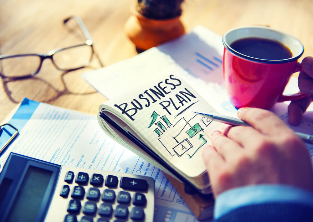 Business owner reviewing a detailed business plan with financial forecasts, strategy notes, and growth objectives, highlighting the importance of business planning for UK entrepreneurs and small businesses.